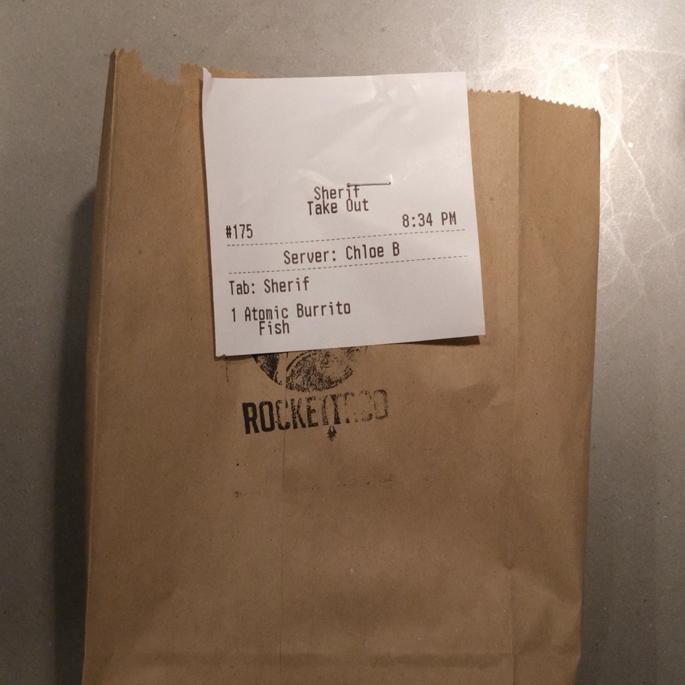 Photo of a burrito in a paper bag.